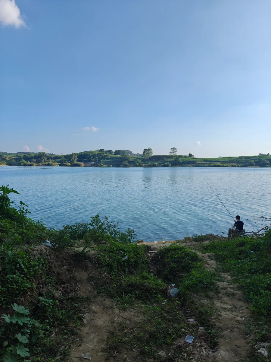 湖岸、远处田地与右下角垂钓人物